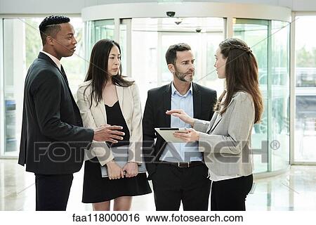 Business people standing and discussing in the hotel lobby View Large Photo Image Stock Photograph - Business people standing and discussing in the hotel lobby. Fotosearch