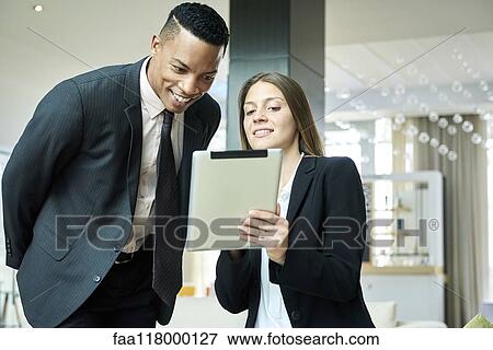 Business people using a digital tablet in hotel lobby View Large Photo Image Stock Photo - Business people using a digital tablet in hotel lobby. Fotosearch