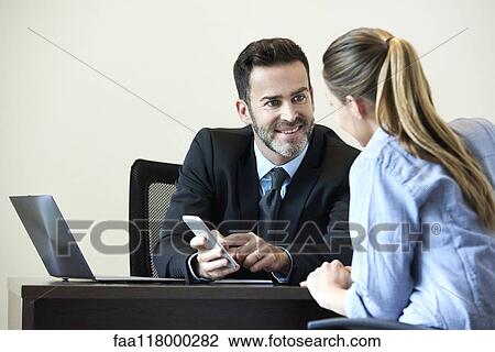 Businessman and businesswoman having meeting in office View Large Photo Image Stock Image - Businessman and businesswoman having meeting in office. Fotosearch