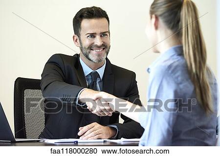 Businessman shaking hands with businesswoman in office View Large Photo Image Stock Image - Businessman shaking hands with businesswoman in office. Fotosearch