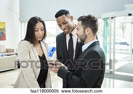 Businessman showing smart phone to his colleagues in hotel View Large Photo Image Stock Photography - Businessman showing smart phone to his colleagues in hotel. Fotosearch