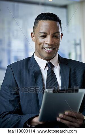 Businessman using digital tablet in office View Large Photo Image Picture - Businessman using digital tablet in office. Fotosearch