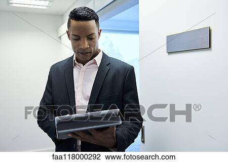 Businessman using digital tablet in hotel lobby View Large Photo Image Stock Image - Businessman using digital tablet in hotel lobby. Fotosearch