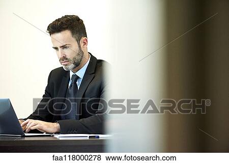 Businessman using laptop in office View Large Photo Image Stock Photo - Businessman using laptop in office. Fotosearch