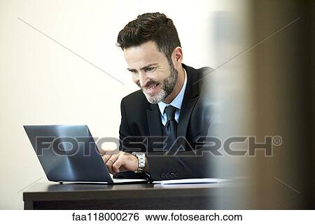 Stock Photograph - Businessman using laptop in office. Fotosearch