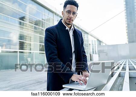 Stock Photo - Businessman using laptop outdoors. Fotosearch