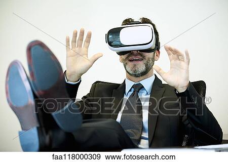 Businessman using virtual reality headset in office View Large Photo Image Stock Photo - Businessman using virtual reality headset in office. Fotosearch