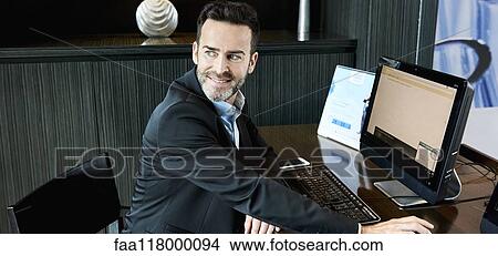 Picture - Businessman working on computer in hotel. Fotosearch