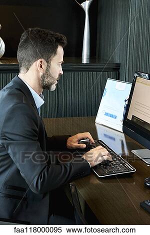 Businessman working on computer in hotel View Large Photo Image Stock Photography - Businessman working on computer in hotel. Fotosearch