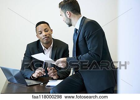 Businessmen discussing document at desk in office View Large Photo Image Stock Photo - Businessmen discussing document at desk in office. Fotosearch