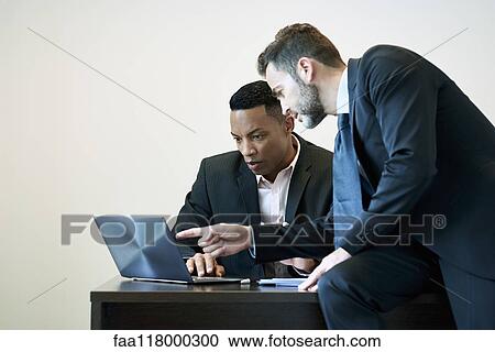 Businessmen discussing project on laptop View Large Photo Image Stock Image - Businessmen discussing project on laptop. Fotosearch