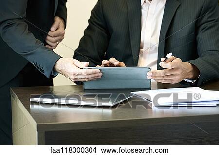Businessmen using a digital tablet in office View Large Photo Image Picture - Businessmen using a digital tablet in office. Fotosearch