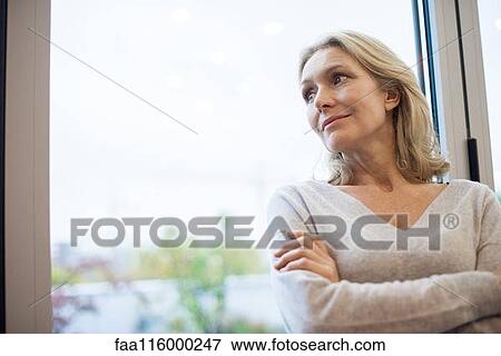 Businesswoman standing near window View Large Photo Image Stock Photo - Businesswoman standing near window. Fotosearch