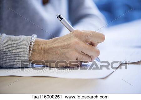 Stock Image - Close-up of businesswoman signing document. Fotosearch