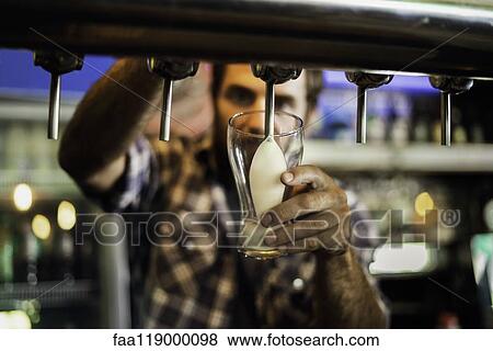 Stock Photo - Close-up of man drawing beer from tap. Fotosearch