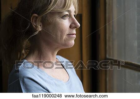 Close-up of thoughtful woman looking through window View Large Photo Image Stock Photo - Close-up of thoughtful woman looking through window. Fotosearch