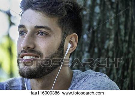 Stock Photograph - Close-up of young man listening to music. Fotosearch