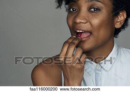 Close-up of young woman taking a pill View Large Photo Image Stock Image - Close-up of young woman taking a pill. Fotosearch