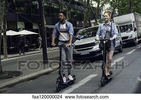 Couple riding push scooters View Large Photo Image Picture - Couple riding push scooters. Fotosearch