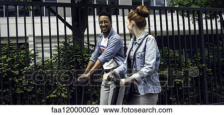 Couple riding push scooters View Large Photo Image Stock Image - Couple riding push scooters. Fotosearch