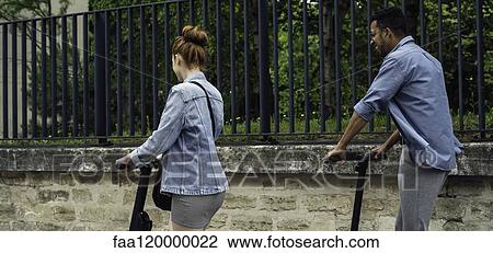 Couple riding push scooters View Large Photo Image Stock Image - Couple riding push scooters. Fotosearch