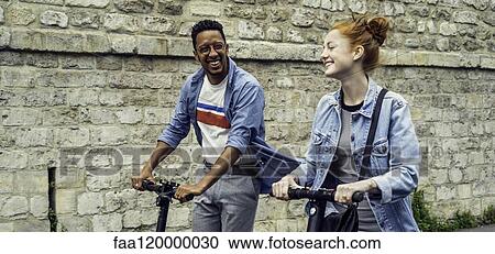 Couple riding push scooters View Large Photo Image Stock Image - Couple riding push scooters. Fotosearch