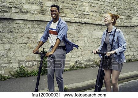 Couple riding push scooters View Large Photo Image Stock Image - Couple riding push scooters. Fotosearch