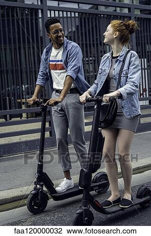 Couple riding push scooters View Large Photo Image Stock Image - Couple riding push scooters. Fotosearch