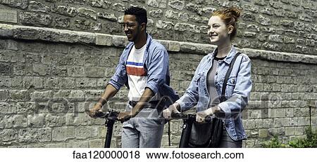 Couple riding push scooters View Large Photo Image Stock Photo - Couple riding push scooters. Fotosearch