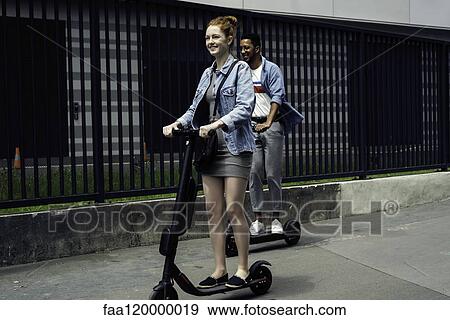 Couple riding push scooters View Large Photo Image Stock Photo - Couple riding push scooters. Fotosearch