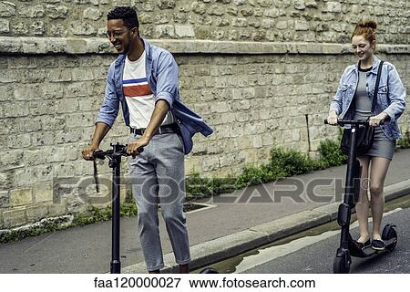 Couple riding push scooters View Large Photo Image Stock Photo - Couple riding push scooters. Fotosearch