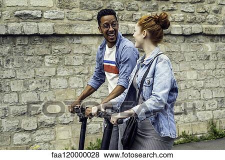 Couple riding push scooters View Large Photo Image Stock Photo - Couple riding push scooters. Fotosearch