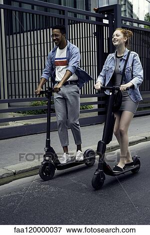 Couple riding push scooters View Large Photo Image Stock Photo - Couple riding push scooters. Fotosearch