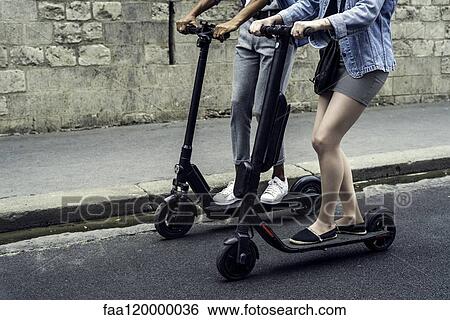Couple riding push scooters View Large Photo Image Stock Photograph - Couple riding push scooters. Fotosearch