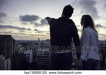 Couple standing on terrace and looking at cityscape View Large Photo Image Stock Photography - Couple standing on terrace and looking at cityscape. Fotosearch