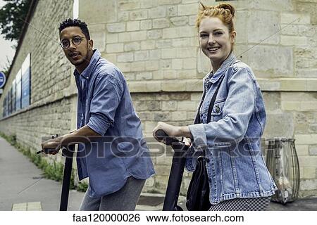 Couple standing with push scooters View Large Photo Image Stock Photograph - Couple standing with push scooters. Fotosearch