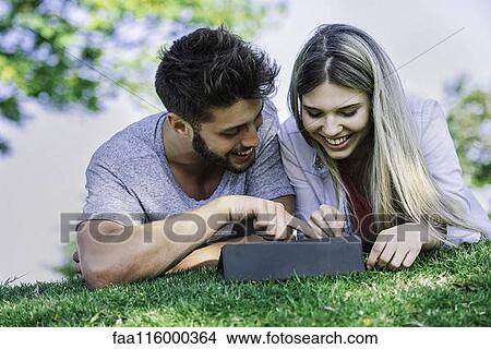 Couple using digital tablet in park View Large Photo Image Picture - Couple using digital tablet in park. Fotosearch