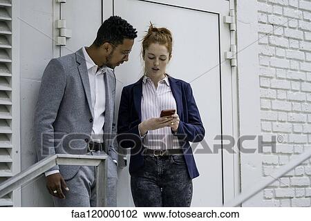 Couple using smart phone outdoors View Large Photo Image Stock Image - Couple using smart phone outdoors. Fotosearch