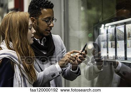 Couple using smartphone at window display View Large Photo Image Stock Image - Couple using smartphone at window display. Fotosearch