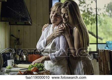 Daughter embracing her mother in kitchen View Large Photo Image Stock Image - Daughter embracing her mother in kitchen. Fotosearch