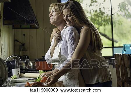 Daughter embracing her mother in kitchen View Large Photo Image Stock Photo - Daughter embracing her mother in kitchen. Fotosearch