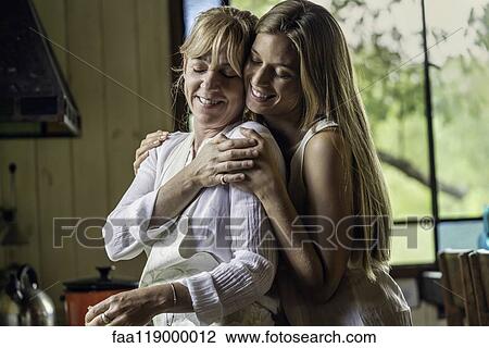Daughter embracing mother in kitchen View Large Photo Image Stock Image - Daughter embracing mother in kitchen. Fotosearch