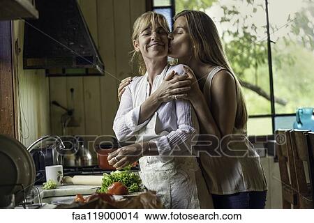 Daughter kissing her mother in kitchen View Large Photo Image Picture - Daughter kissing her mother in kitchen. Fotosearch