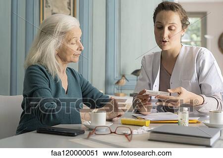 Stock Image - Doctor explaining medicine box to patient. Fotosearch