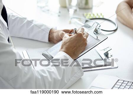 Stock Image - Doctor writing prescription on clipboard. Fotosearch