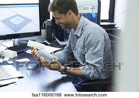 Stock Photo - Engineer holding heat sink in office. Fotosearch