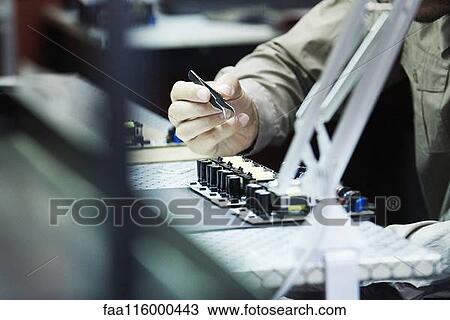 Stock Image - Engineer soldering circuit board in office. Fotosearch