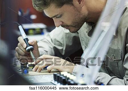 Stock Photography - Engineer soldering circuit board in office. Fotosearch