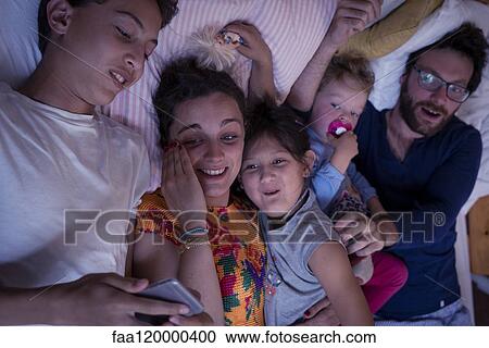 Family lying on bed at home View Large Photo Image Stock Image - Family lying on bed at home. Fotosearch