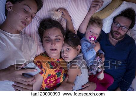 Family lying on bed at home View Large Photo Image Stock Photo - Family lying on bed at home. Fotosearch